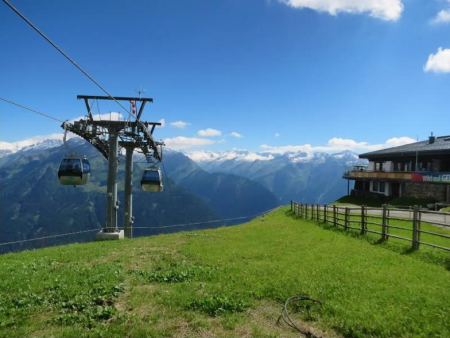 Gondelbaan met cabines en een bergrestaurant op een groene weide – Zirbenweg op de Wildkogel, Wildkogel Arena